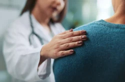 Female doctor consoling patient with her hand on her shoulder