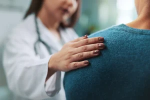 Female doctor consoling patient with her hand on her shoulder