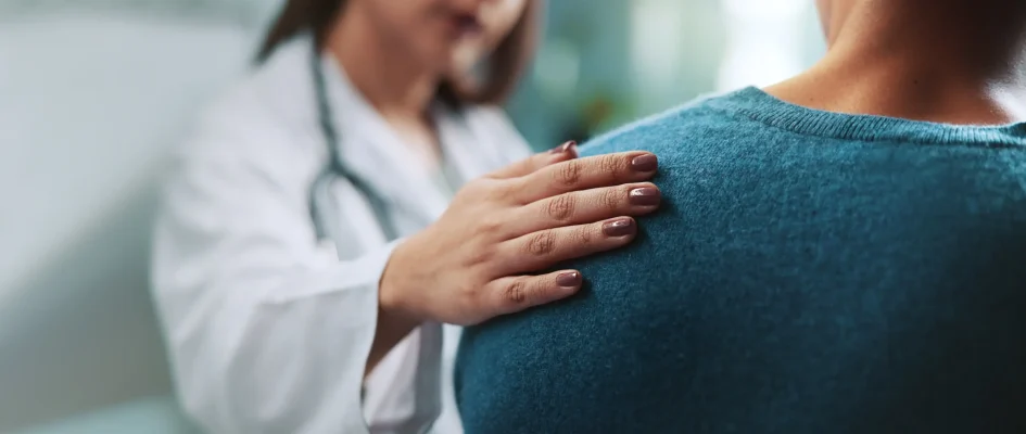 Female doctor consoling patient with her hand on her shoulder