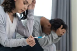 Woman sitting alongside partner holding pregnancy test in hand